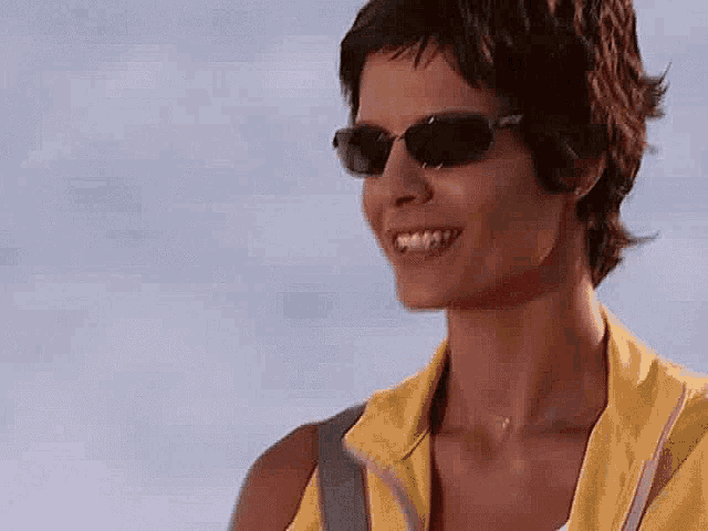 a close up of a woman wearing sunglasses and a yellow jacket .