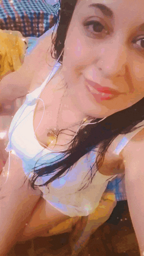 a woman wearing a white tank top and headphones smiles for the camera