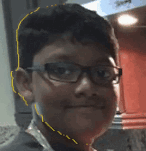 a boy wearing glasses has a yellow line drawn around his face