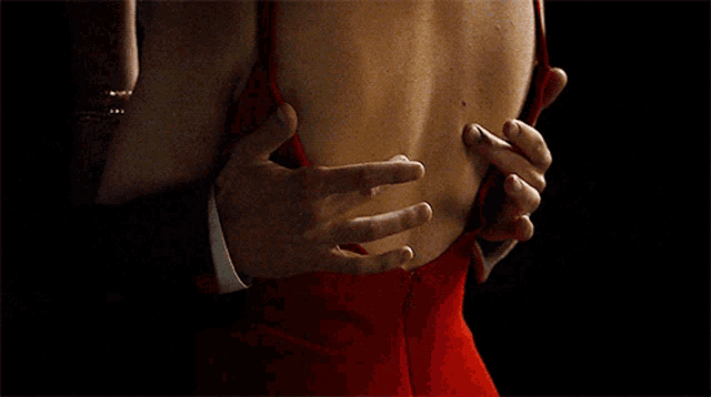 a woman in a red dress is being held by a man in a suit