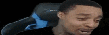 a man is sitting in a gaming chair with his mouth open and making a funny face .