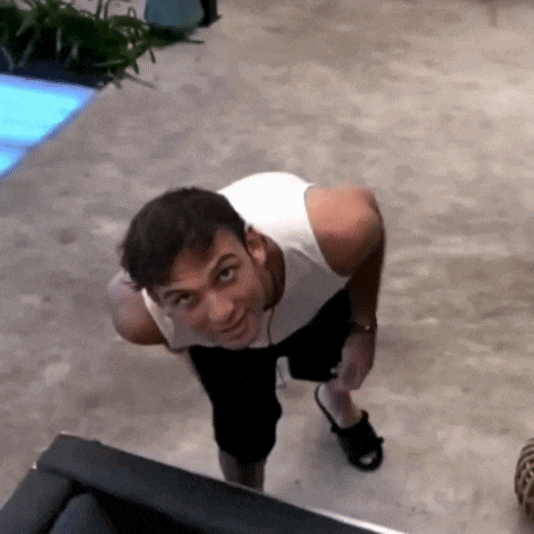 a man in a white tank top and black shorts is looking up at the camera .