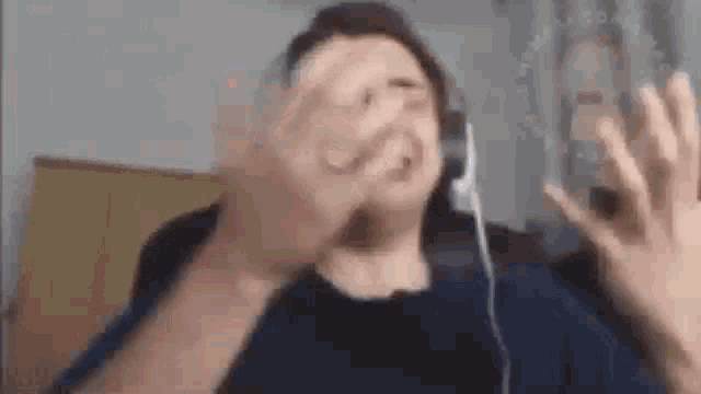 a man wearing headphones is making a funny face while looking at his phone .
