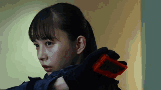 a girl with a black glove is holding a red object that says ' a ' on it