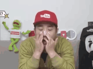 a man wearing a red hat with the word youtube on it is blowing his nose .