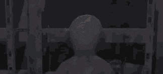 a teletubbies teddy bear is standing in a dark room in front of a window .