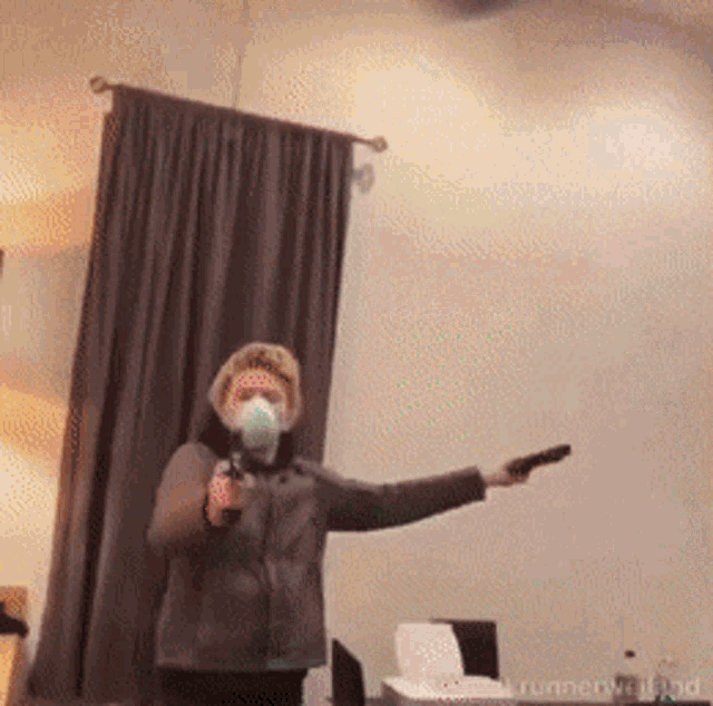a woman wearing a mask is holding a gun in a room