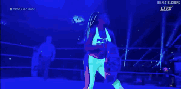 a woman in a yellow tank top is holding up a wrestling belt in front of a crowd ..