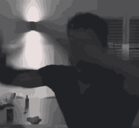 a man in a black shirt is standing in a dark room with his arms outstretched
