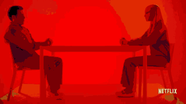a man and a woman are sitting at a table with netflix written on the bottom right