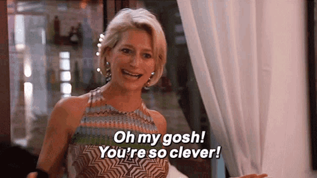 a woman in a colorful dress is laughing and saying oh my gosh you 're so clever .