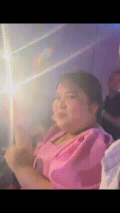 a girl in a pink dress is sitting in a dark room