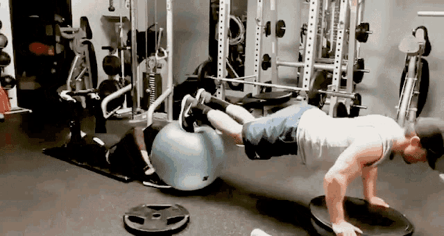 a man is doing push ups in a gym with a pilates ball in the background