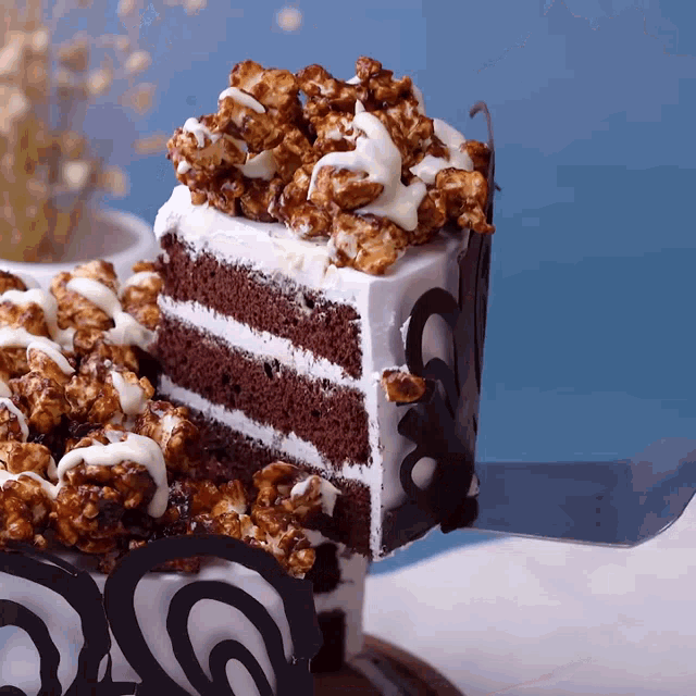 a slice of chocolate cake with popcorn on top is being cut