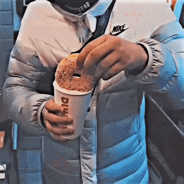 a person wearing a nike jacket is holding a donut in their hand