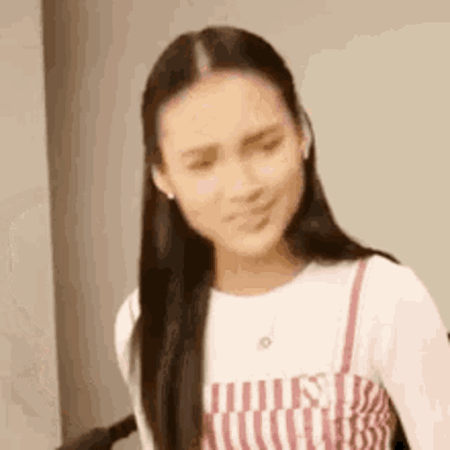 a close up of a woman making a funny face while wearing a striped dress and a white shirt .