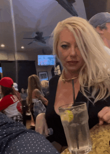 a blonde woman sitting at a table with a glass of water