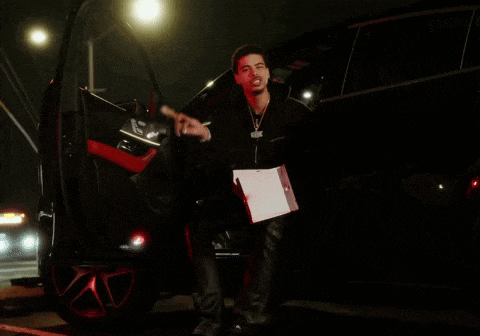 a man is getting out of a car at night holding a bag