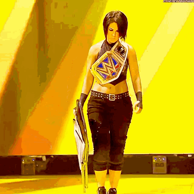 a woman is holding a shield and wearing a wrestling belt with the letters wwe on it
