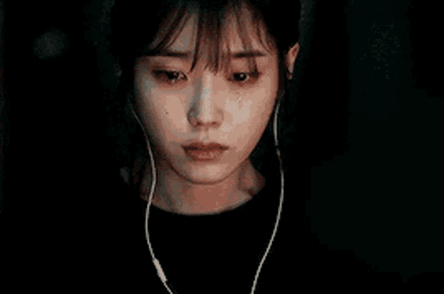 a woman is crying while listening to music with headphones on .