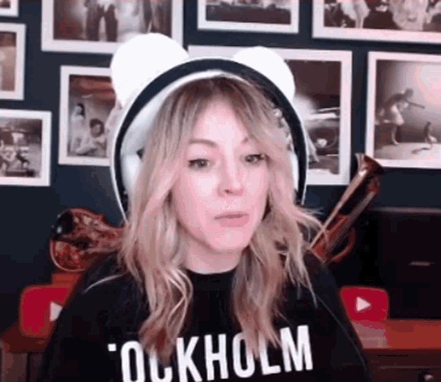 a woman wearing headphones and a black shirt is sitting in front of a wall with pictures .