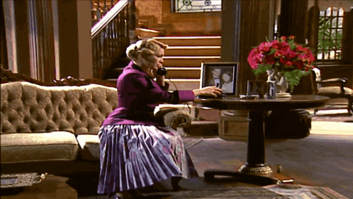 a woman is sitting on a couch talking on a phone