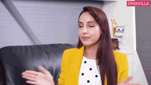 a woman in a yellow jacket sits on a black couch