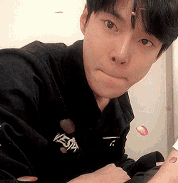 a young man wearing a black jacket with the word vesta embroidered on it