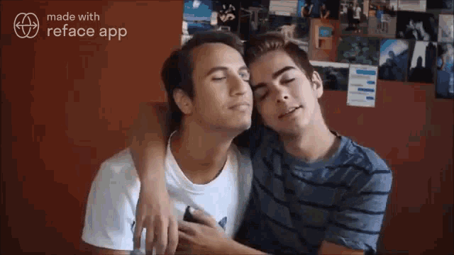 two young men are hugging each other in front of a red wall .