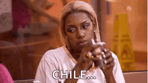 a woman is sitting at a table with a drink in her hand and a sign that says `` chile '' .