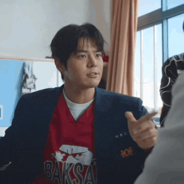 a young man wearing a red shirt that says baksa