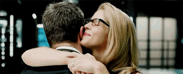 a woman with glasses is kissing a man on the cheek