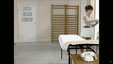 a woman is standing in front of a table with the words npo fake news written on it