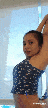 a woman in a crop top and thong is stretching her arms .
