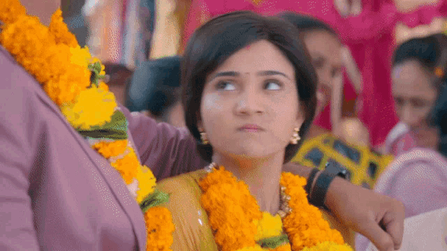 a woman wearing a garland of yellow flowers is looking up at something