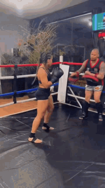 a man and a woman are boxing in a ring with a sign on the wall that says ' boxing club '