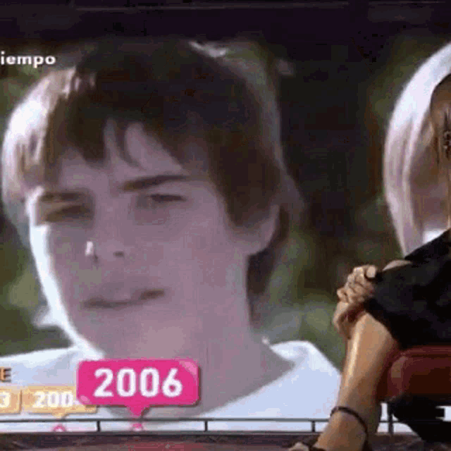 a woman is sitting in front of a television screen with a picture of a boy .