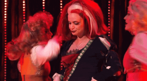 a woman with red hair and white streaks is dancing on stage