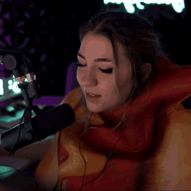 a woman sitting in front of a microphone wearing an inflatable hot dog costume