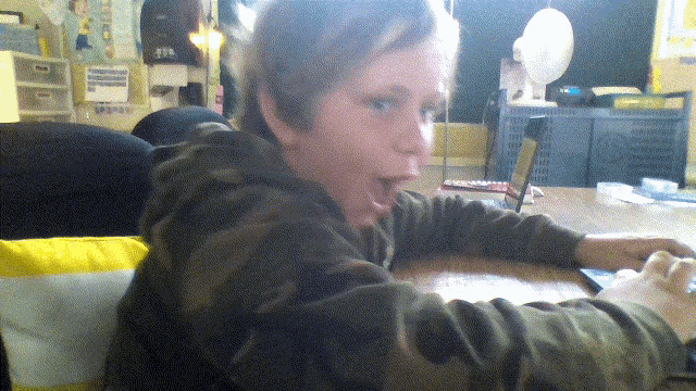 a boy in a camo sweatshirt is sitting at a table with a laptop