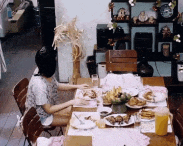 a woman sits at a table with plates of food