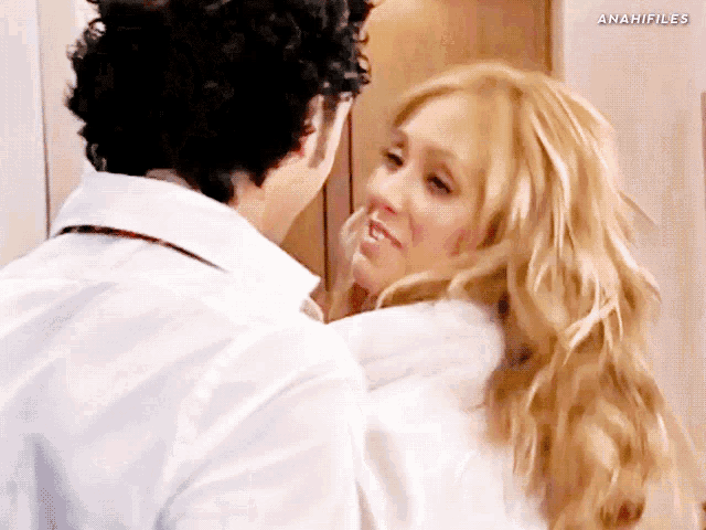 a man and a woman are kissing in front of a sign that says anah files
