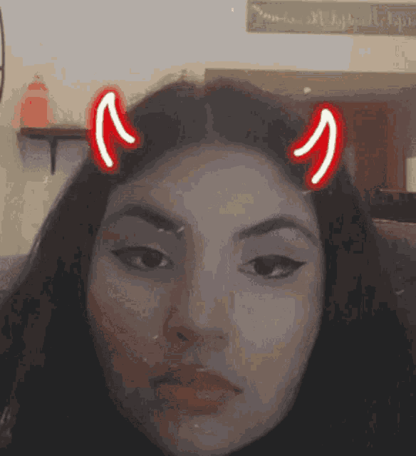 a close up of a woman 's face with red horns on her head