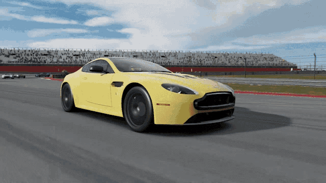 a yellow sports car is driving down a track