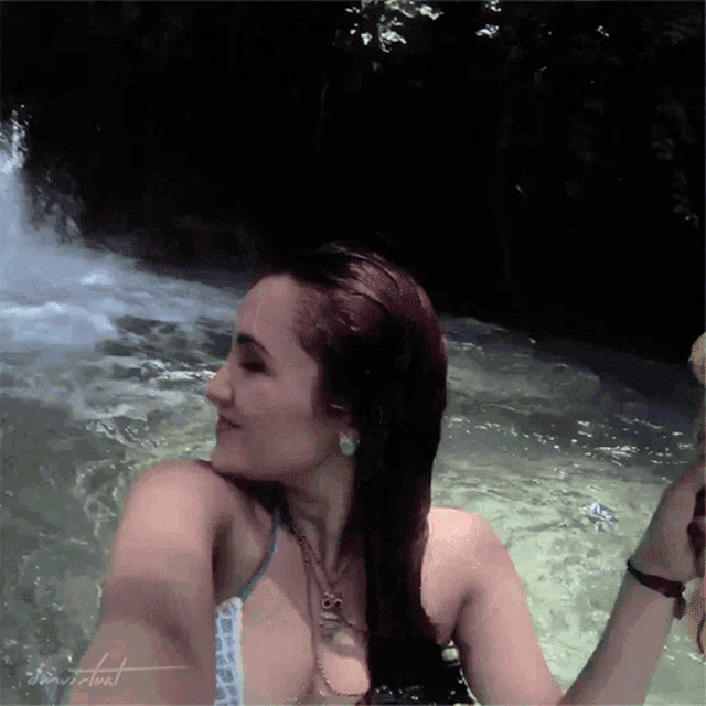 a woman in a bikini is taking a selfie in a pool with the word virtual written on the bottom right