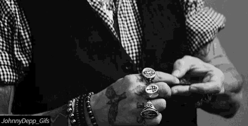 a black and white photo of a man 's hands with rings on them
