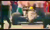 a blurred image of a race car with a yellow helmet on the driver