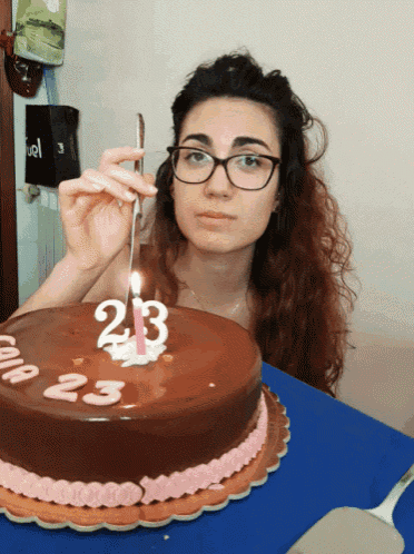 a woman is lighting a candle on a cake that has the number 23 on it