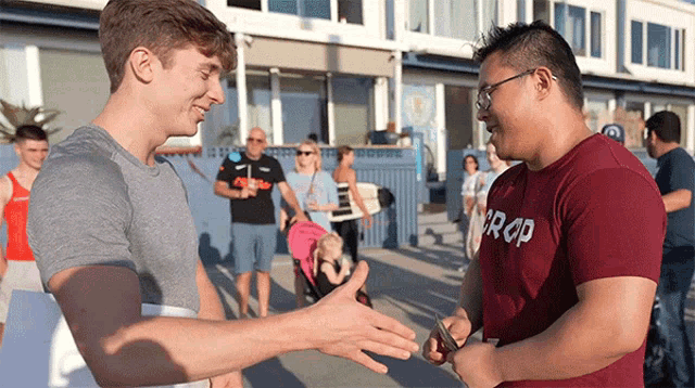 a man wearing a crop t-shirt shakes hands with another man
