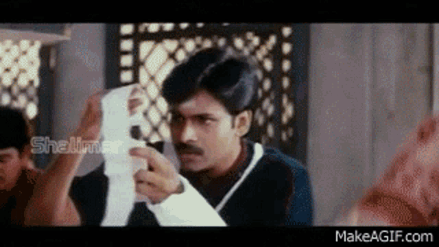 a man is holding a piece of paper in his hand and looking at it .